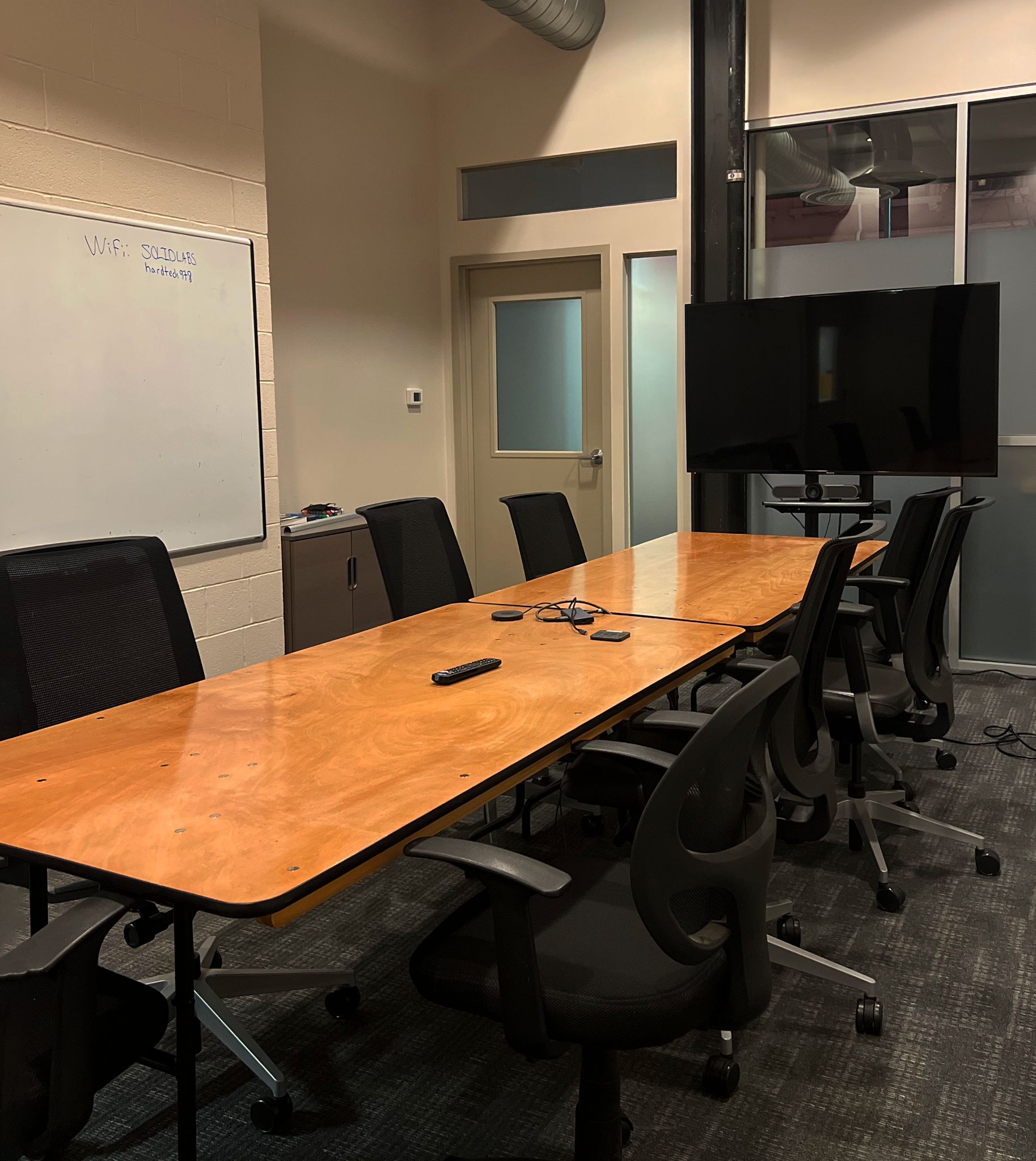 Professional conference room with large table, whiteboard, and video display