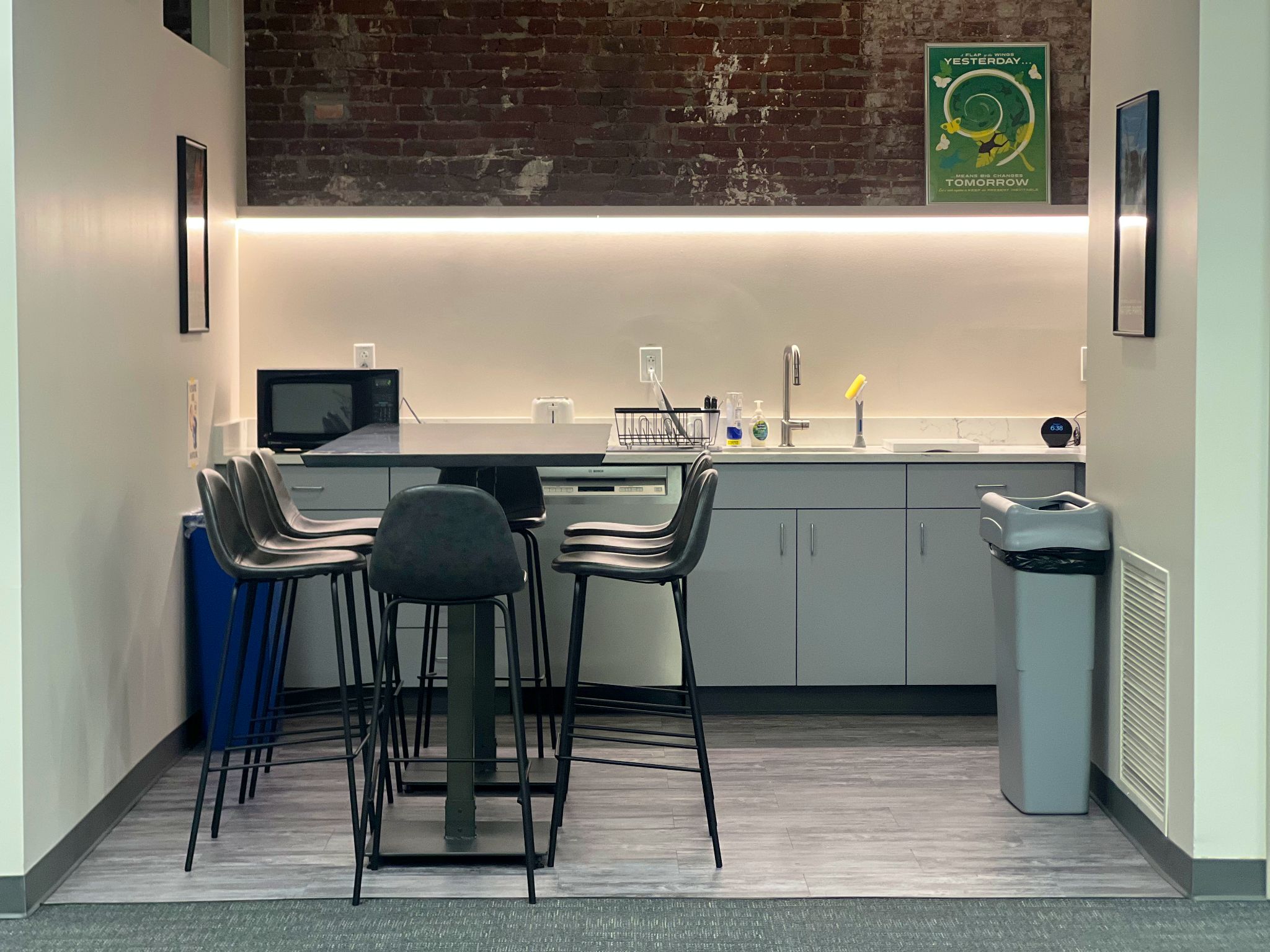 Shared kitchenette with counter seating, appliances, and exposed brick